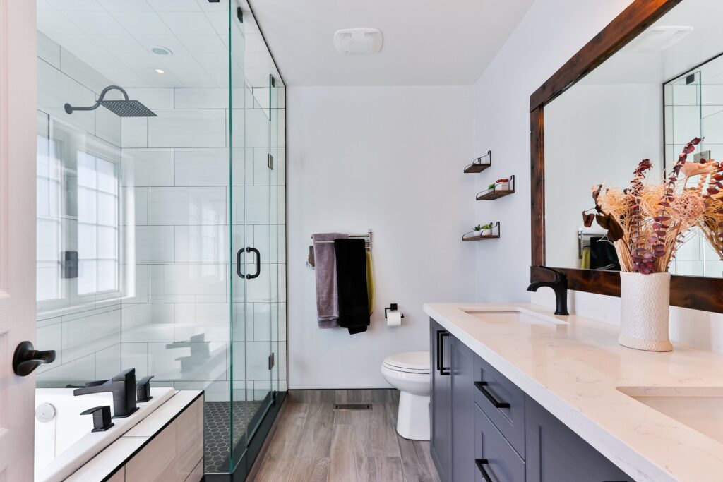 Renovated bathroom featuring a spacious walk-in shower with sleek glass doors, modern fixtures, and stylish tile work. Soft lighting enhances the contemporary design, creating a serene and inviting atmosphere - contact us 