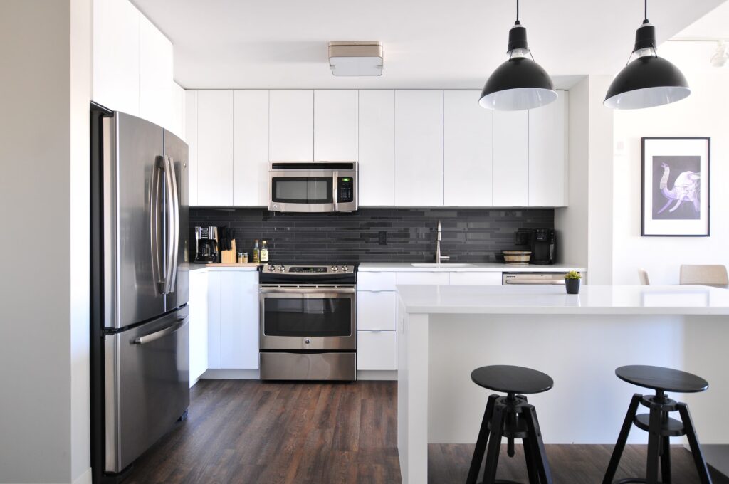 Modern kitchen installation featuring sleek cabinetry, stainless steel appliances, and a spacious island with bar stools. Bright lighting illuminates the open layout, showcasing a blend of contemporary design and functionality - contact us 